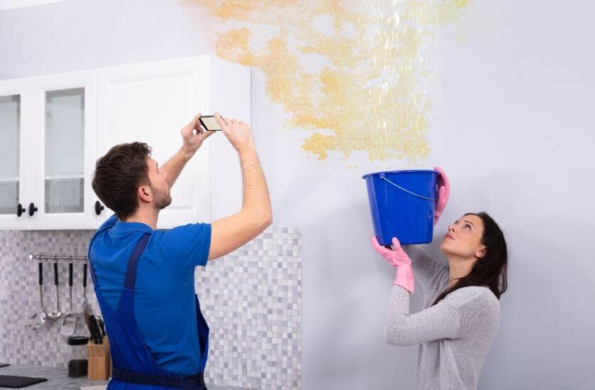 Technician documenting ceiling water leak during inspection in Wilmington
